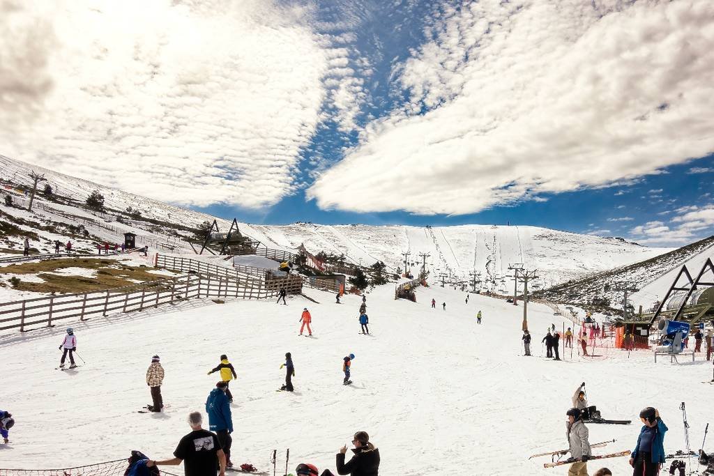 Skiers enjoying the slopes and ski lifts at Sierra de Guadarrama mountains near Madrid, Spain, on a sunny winter day. Madrid Winter Travel Guide 2025: Best Things to Do, See & Eat.