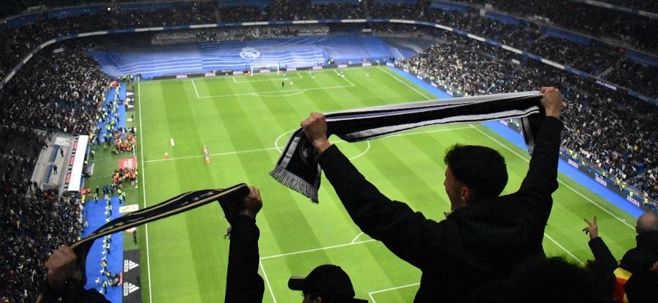 Fans cheering with scarves at Santiago Bernabéu Stadium in Madrid during a Real Madrid football match. Madrid Winter Travel Guide 2025: Best Things to Do, See & Eat.
