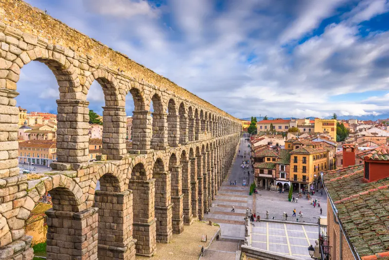 Ancient Roman aqueduct of Segovia, Spain, with stone arches overlooking the old town and main square. Madrid Winter Travel Guide 2025: Best Things to Do, See & Eat.