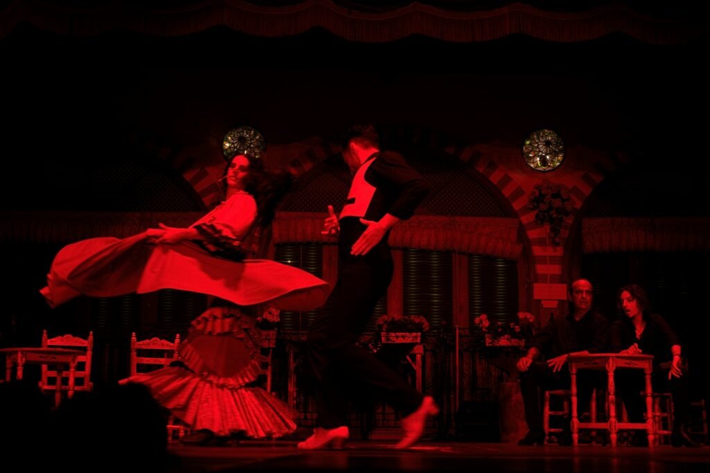 Flamenco dancers performing on stage in Madrid, Spain, with dramatic red lighting and live musicians in the background. Madrid Winter Travel Guide 2025: Best Things to Do, See & Eat.