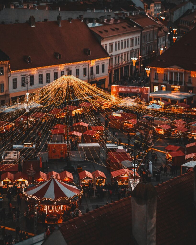 Plaza Mayor Christmas market in Madrid at night with festive lights, decorated stalls, and a carousel creating a magical holiday atmosphere. Madrid Winter Travel Guide 2025: Best Things to Do, See & Eat.